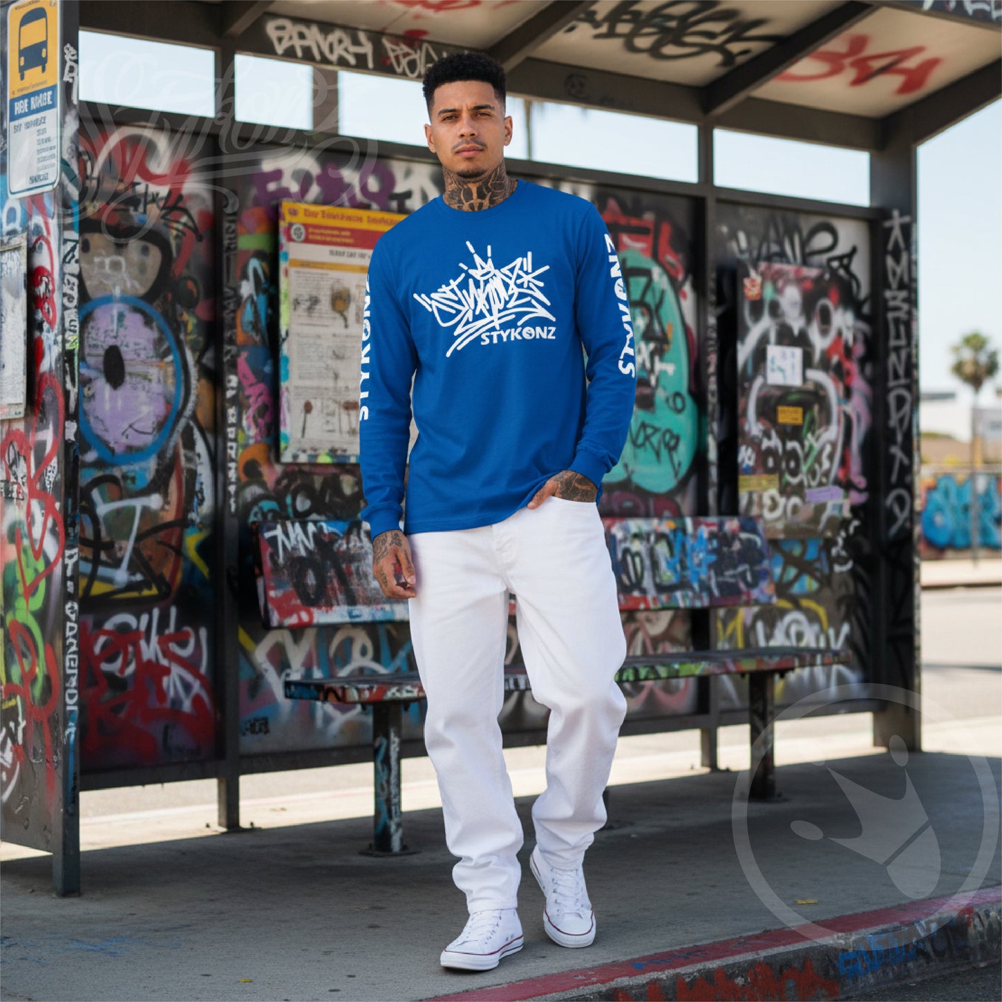 Person wearing a blue sweatshirt with a Stykonz Tag in front of a graffiti-covered bus stop.