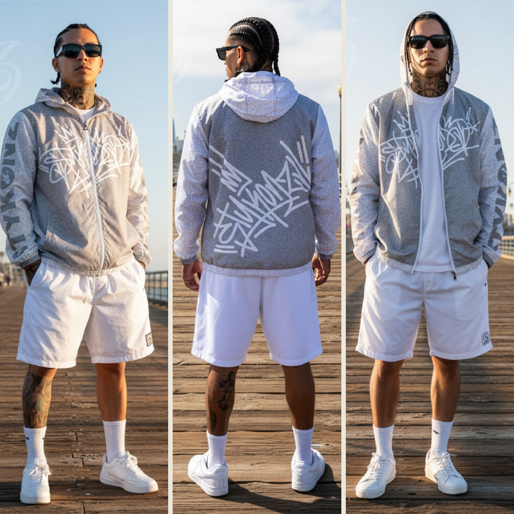Man wearing a gray hoodie with white Stykonz Tag and white shorts on a wooden boardwalk.
